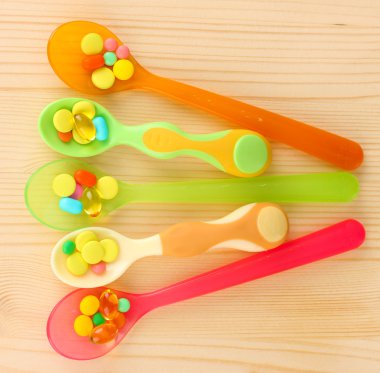 ahşap arka plan üzerinde renkli hapları ile plastik kaşık