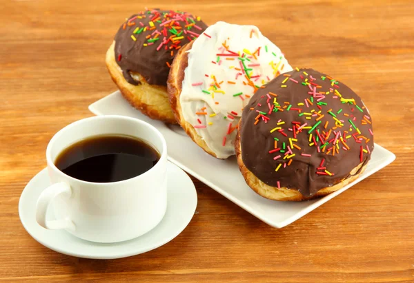 Tasty donuts on color plate on wooden background — Stock Photo, Image