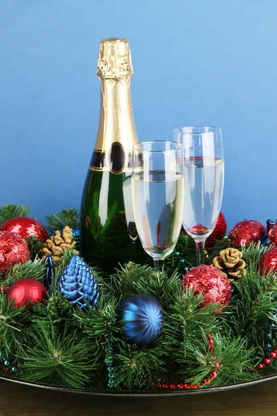 Schöner Weihnachtskranz in Komposition mit Champagner auf blauem Hintergrund — Stockfoto