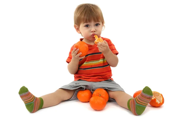 Niedlicher kleiner Junge isst Mandarinen, isoliert auf weiß — Stockfoto