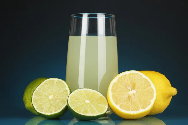 Läckra citronsaft i glas och lime och citroner bredvid den på Mörkblå bakgrund — Stockfoto