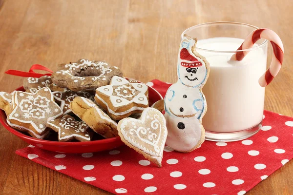 Christmas treats on plate and glass of milk on wooden table close-up — Stock Photo, Image