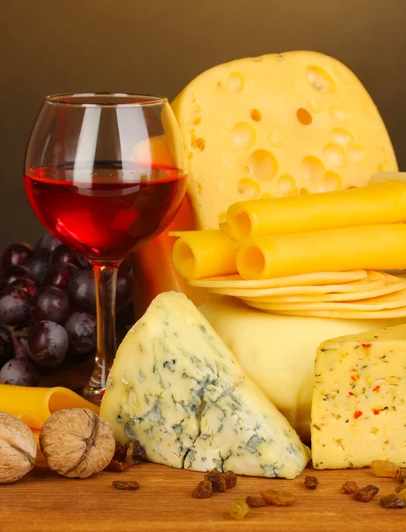 Various types of cheese on wooden table on brown background — Stock Photo, Image