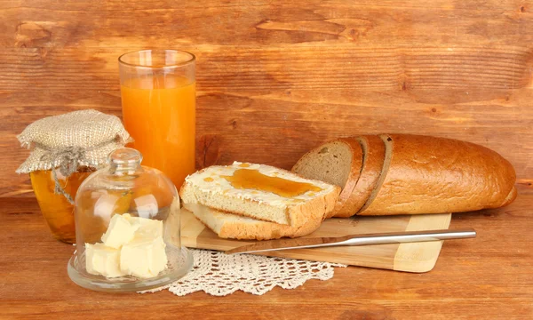 Unt pe farfurie de sticlă cu capac de sticlă și pâine proaspătă, miere pe fundal din lemn — Fotografie, imagine de stoc
