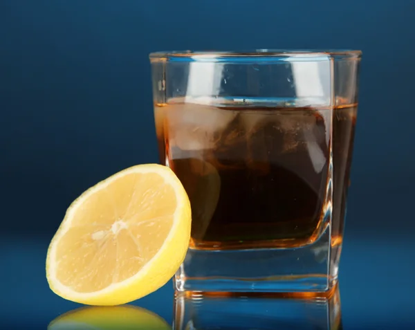 Bicchiere di whisky con ghiaccio e limone su sfondo blu — Foto Stock