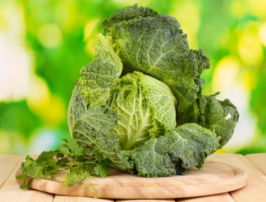 Fresh savoy cabbage on wooden table on natural background
