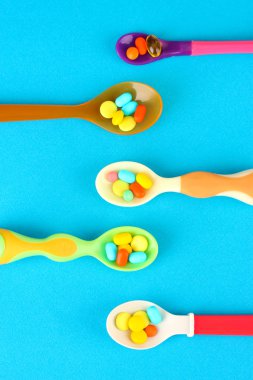 plastik kaşık ile mavi arka plan üzerinde renkli hapları