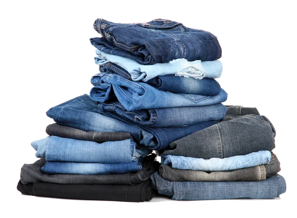 Många jeans staplade i en isolerad på vita högar — Stockfoto