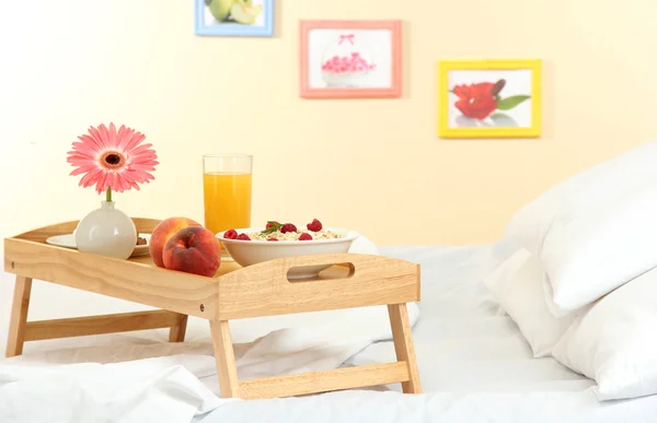 Houten dienblad met licht ontbijt op bed — Stockfoto