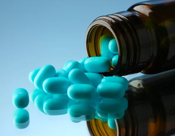 Pastillas en botella, sobre fondo azul —  Fotos de Stock