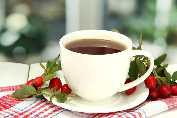 Šálek čaje s moderní růže, na dřevěný stůl — Stock fotografie