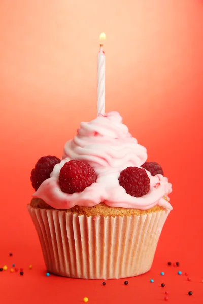 Smakelijke verjaardag cupcake met kaars, op rode achtergrond — Stockfoto