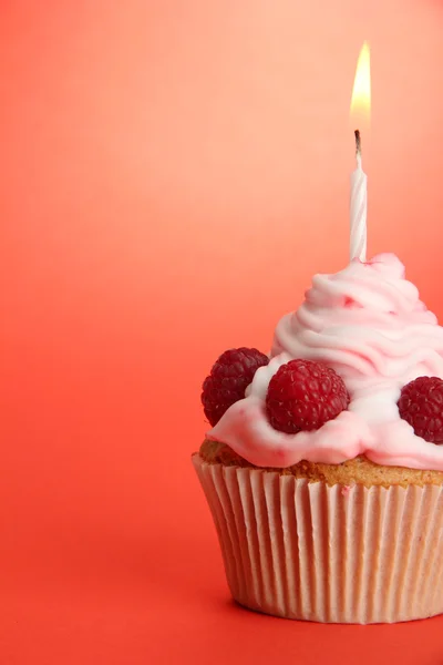 Вкусный праздничный кекс со свечой, на красном фоне — стоковое фото