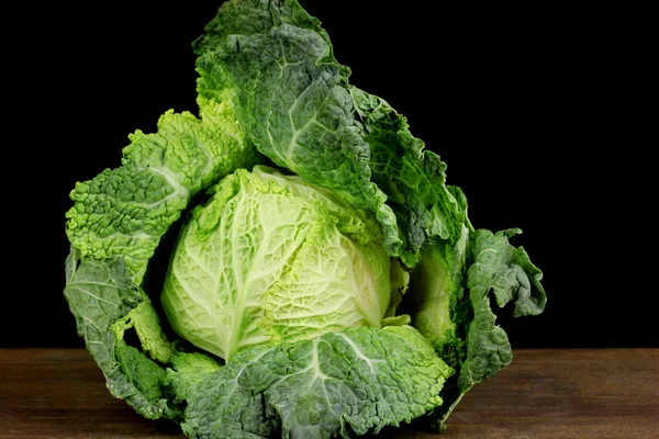 Färska savojkål på träbord på svart bakgrund — Stockfoto