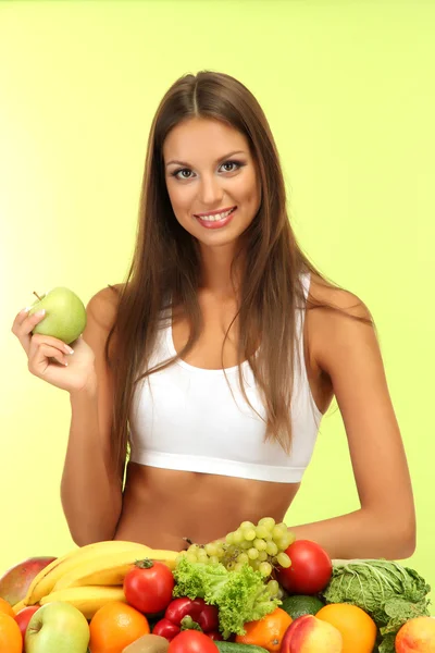 Красивая молодая женщина с фруктами и овощами, на зеленом фоне — стоковое фото