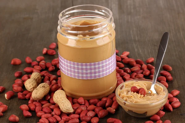 Вкусное арахисовое масло в банке на деревянном столе крупным планом — стоковое фото