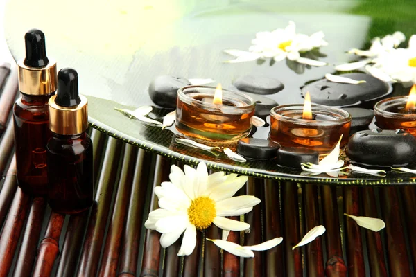 Piedras de spa con flores y velas en agua en el plato — Foto de Stock