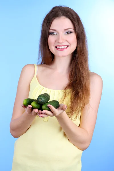 Mooie vrouw met komkommers op blauwe achtergrond — Stockfoto