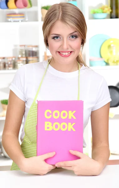 Una joven en la cocina con libro de cocina — Foto de Stock