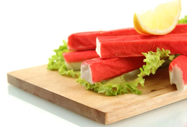 Bastoncini di granchio con foglie di lattuga e limone sul tagliere isolato su bianco — Foto Stock