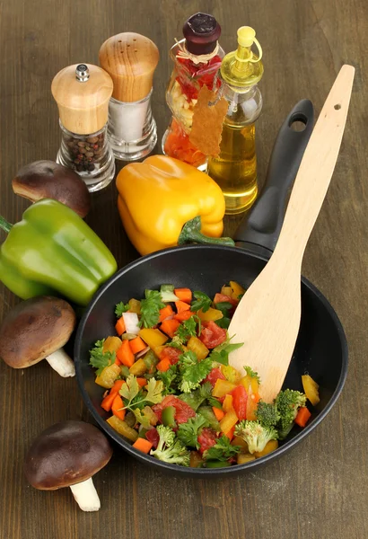 Verdure fresche affettate in padella con spezie e ingredienti su tavola di legno — Foto Stock