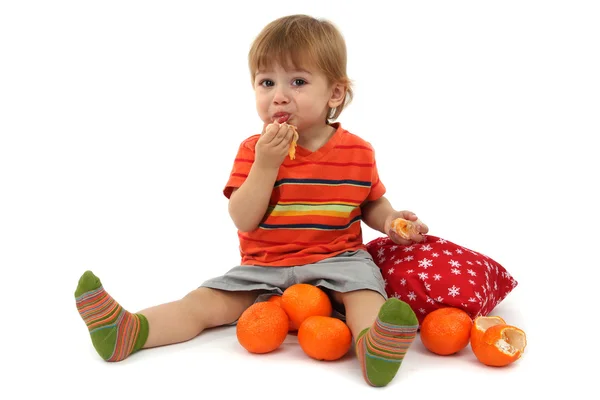 Schattige kleine jongen eten mandarijnen, geïsoleerd op wit — Stockfoto