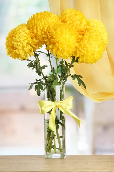 Leuchtend gelbe Chrysanthemen in Glasvase, auf Holztisch — Stockfoto