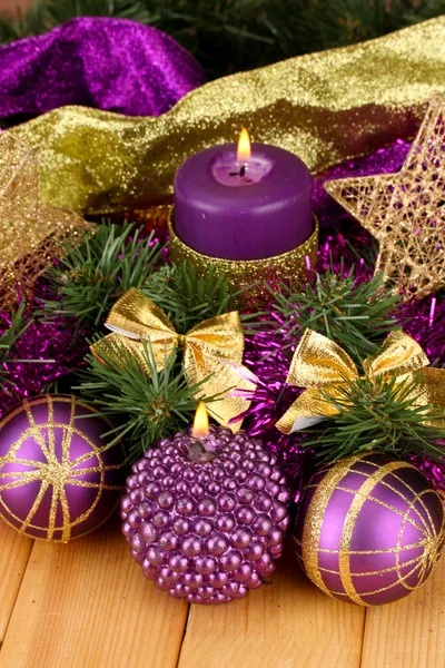 Christmas composition with candles and decorations in purple and gold colors on wooden background — Stock Photo, Image