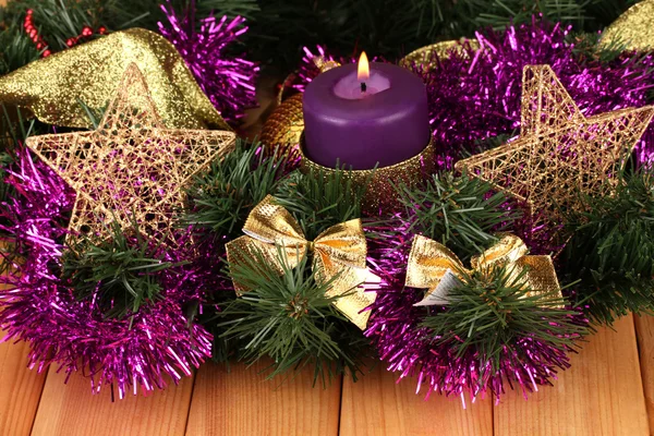 Рождественская композиция со свечами и украшениями в фиолетовых и золотых тонах на деревянном фоне — стоковое фото