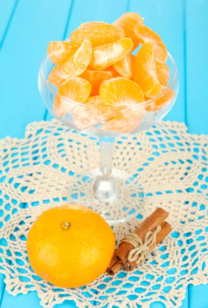 Chutné mandarine výsečí ve skleněné míse na modrém pozadí — Stock fotografie