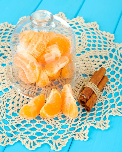 Rebanadas de mandarina en platillo bajo cubierta de vidrio sobre fondo azul —  Fotos de Stock