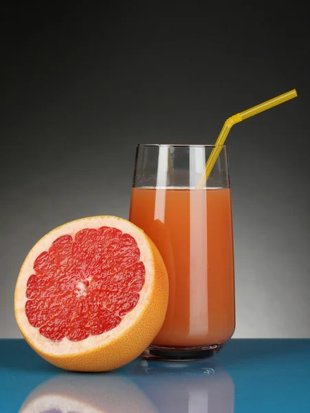 Delicioso zumo de pomelo en vaso y pomelo junto a él sobre fondo azul oscuro —  Fotos de Stock