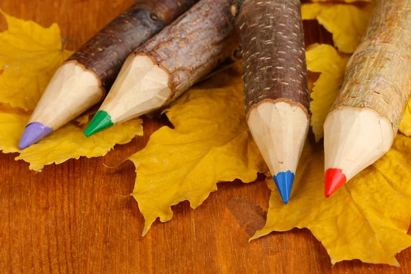 Lápices de madera de colores con hojas de otoño en la mesa de madera — Foto de Stock