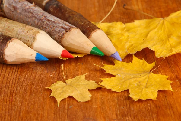 Lápis de madeira coloridos com folhas de outono na mesa de madeira — Fotografia de Stock