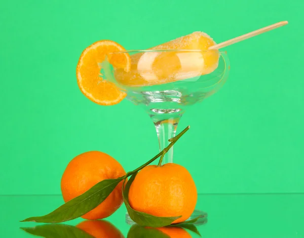 Yellow fruit juice ice in vase on green background — Stock Photo, Image
