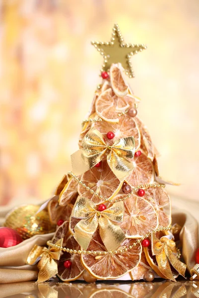 Beau sapin de Noël de citrons secs avec décor, sur fond jaune — Photo