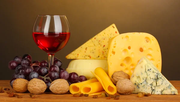 Various types of cheese on wooden table on brown background — Stock Photo, Image