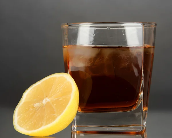 Glas Whisky mit Eis und Zitrone auf grauem Hintergrund — Stockfoto