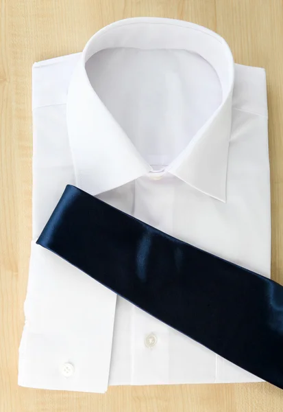 New white man 's shirt with color tie on wooden background — стоковое фото