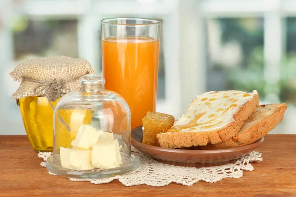 Mantequilla en platillo de vidrio con tapa de vidrio y pan fresco, miel, sobre fondo brillante —  Fotos de Stock