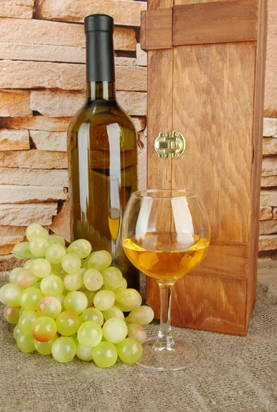 Composición de vino, caja y uvas en la mesa sobre fondo de pared de ladrillo — Foto de Stock