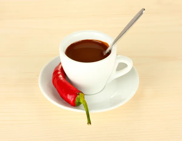 White cup with hot chocolate and chili pepper on wooden background Stock Photo