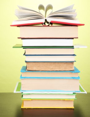 Stack of interesting books and magazines on wooden table on green background clipart