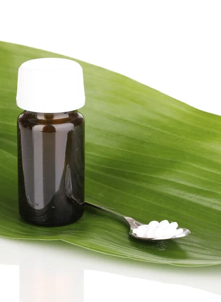 Medicine bottle with tablets on green leaf isolated on white — Stock Photo, Image