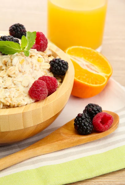 Saporita farina d'avena con bacche e bicchiere di succo, su tavolo di legno — Foto Stock