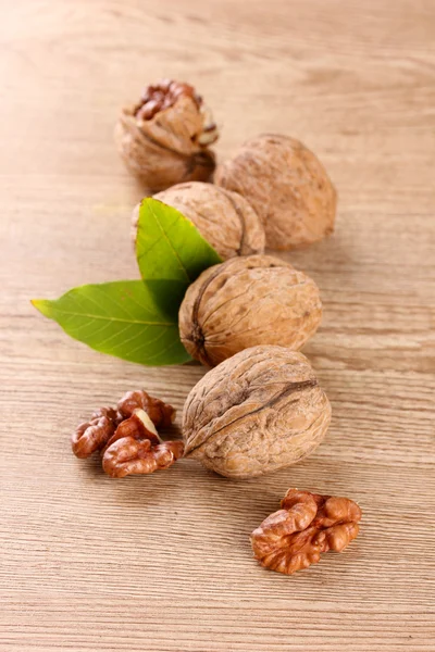 Walnuts with green leaves, on wooden background — Stock Photo, Image