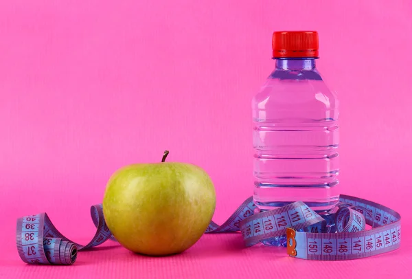 Bottle of water, apple and measuring tape on pink background — Stock Photo, Image