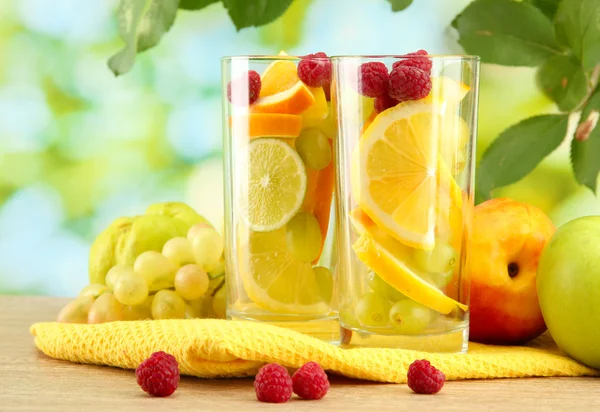 Glasses citrus fruits and raspberries, on green background — Stock Photo, Image