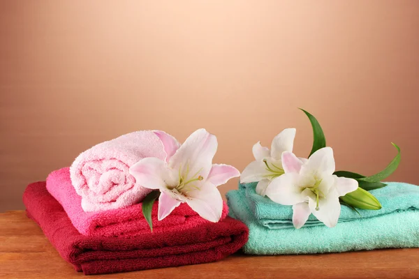 Stack of towels with pink lily on a brown background — Stock Photo, Image