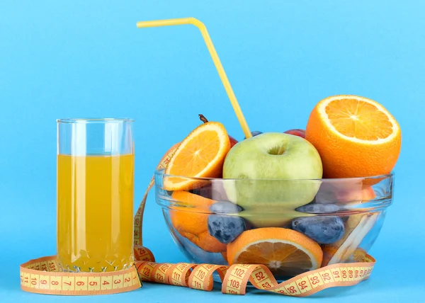 Cuenco de vidrio con fruta para dieta y jugo sobre fondo azul —  Fotos de Stock